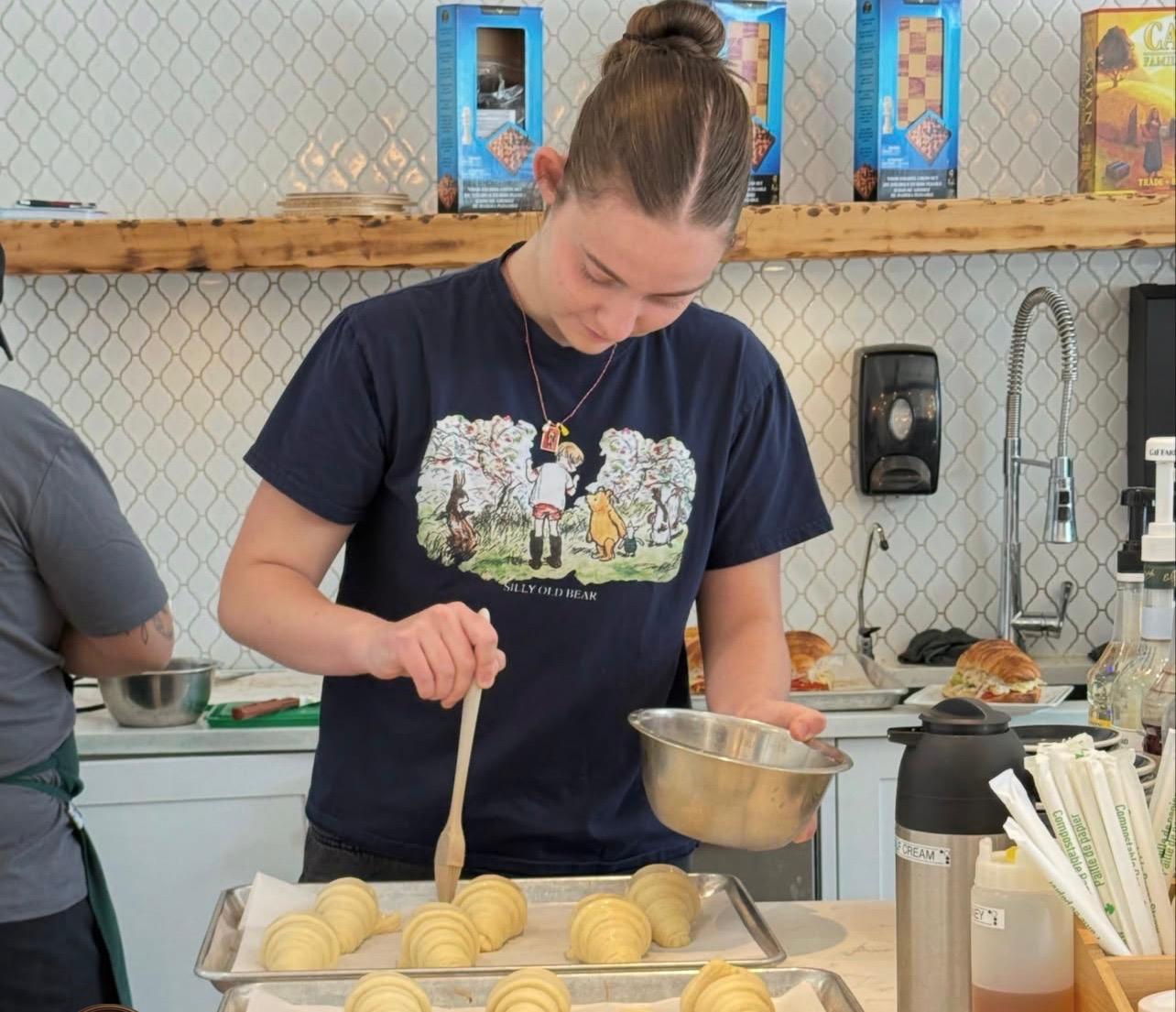 Jayme glazing a tray of croissants in the café kitchen